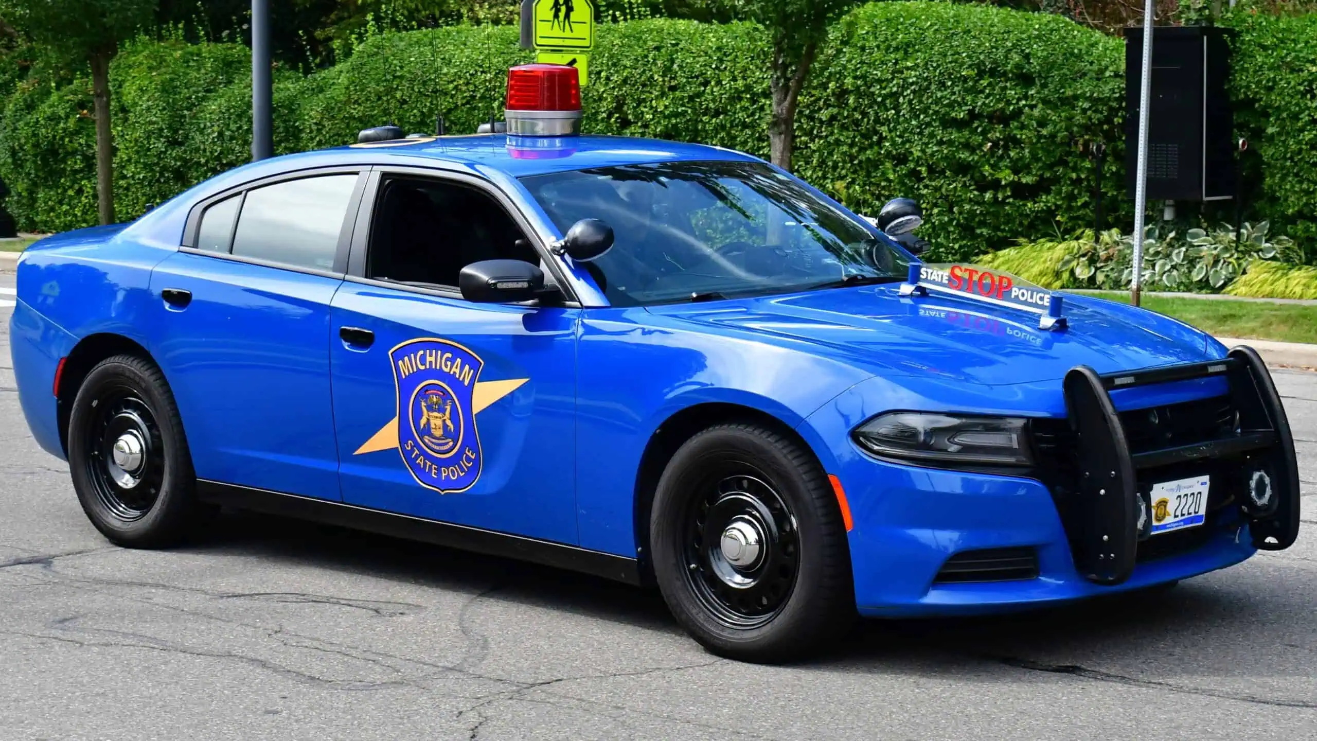 Blue Michigan State Police Dodge Charger with its distinctive red roof beacon parked on a street.