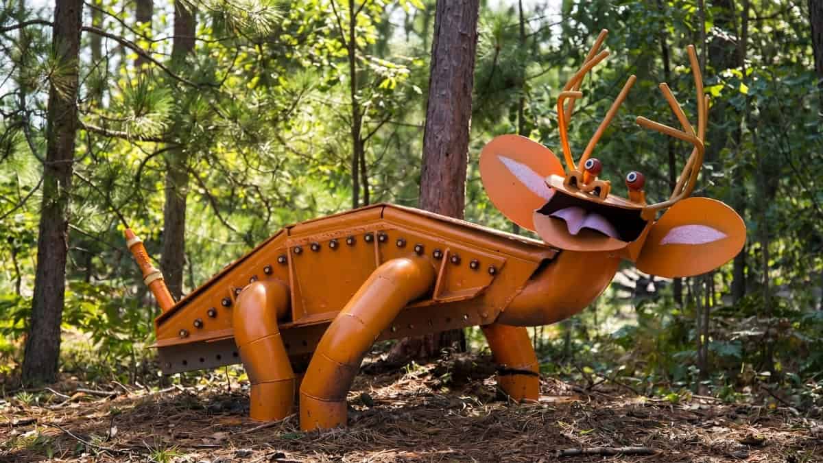 orange creature sculpture in the woods