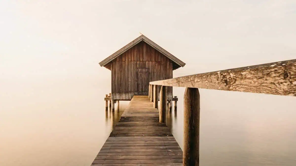 Small wooden cabin at the end of a dock on a calm lake