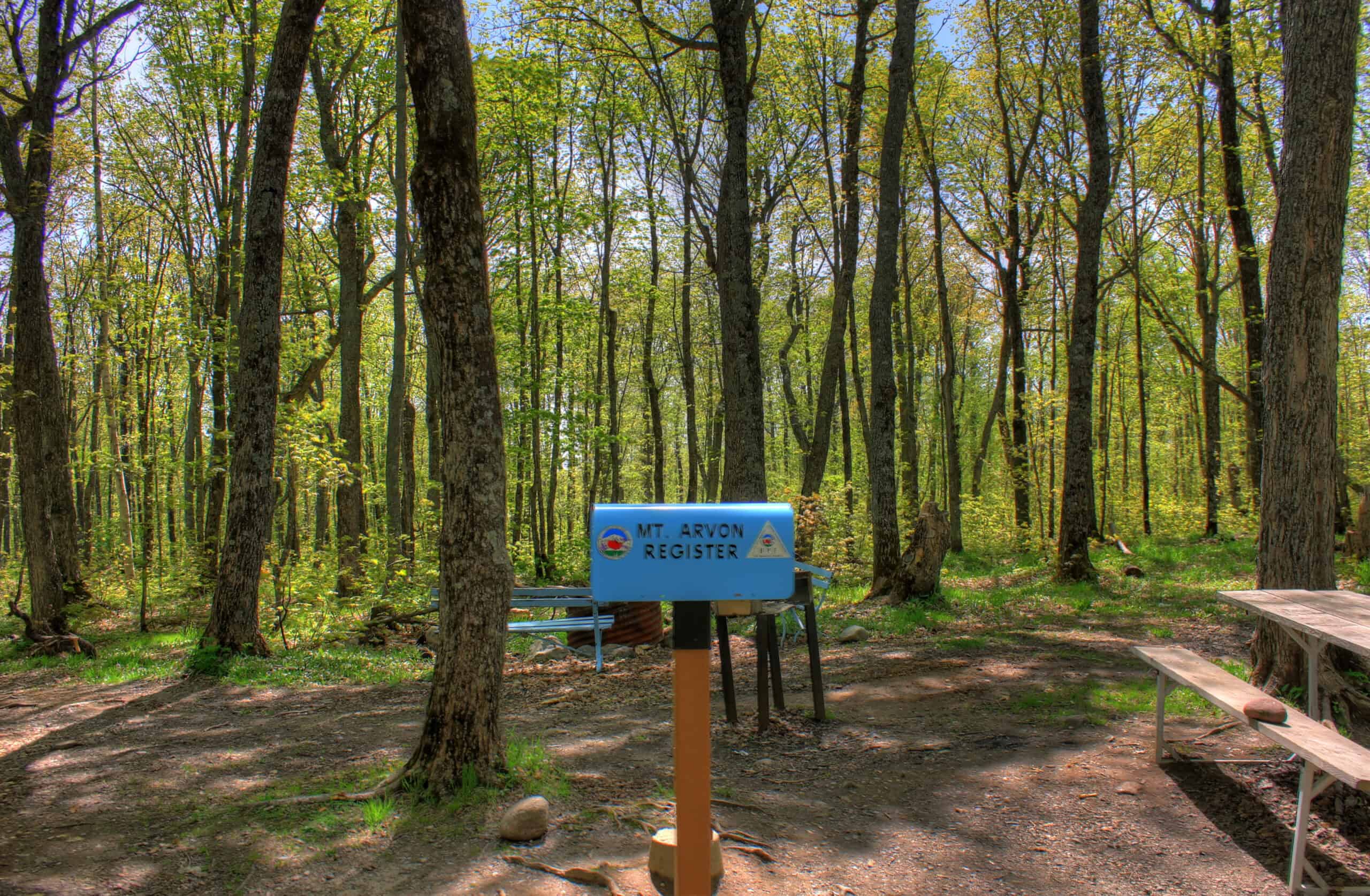 A mailbox on a post in a small forest clearing at the summit of Mount Arvon, holding the visitor sign-in register.