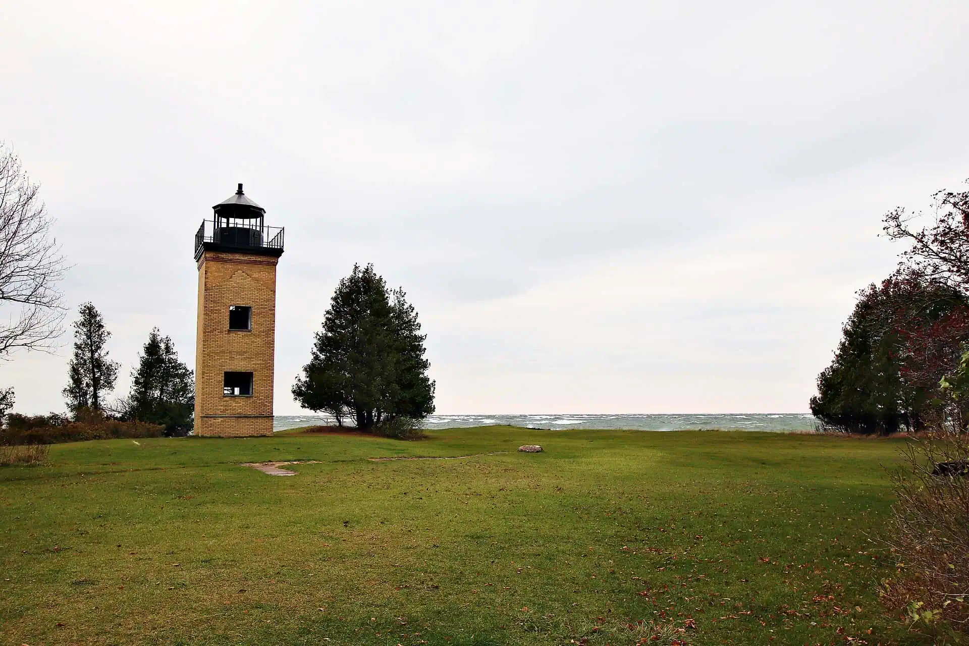 The square brick tower of the Peninsula Point Lighthouse standing above trees at the tip of the Stonington Peninsula.