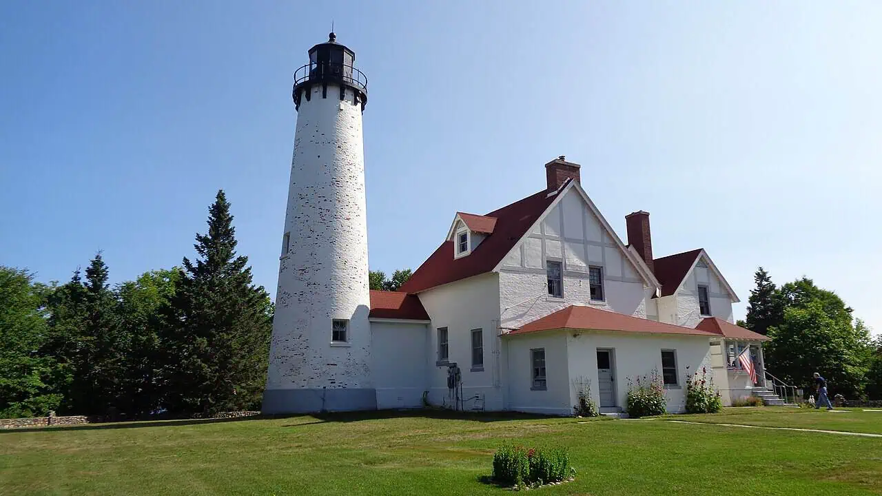 The white brick tower and keeper’s dwelling of Point Iroquois Lighthouse on a bluff above Whitefish Bay, Michigan.