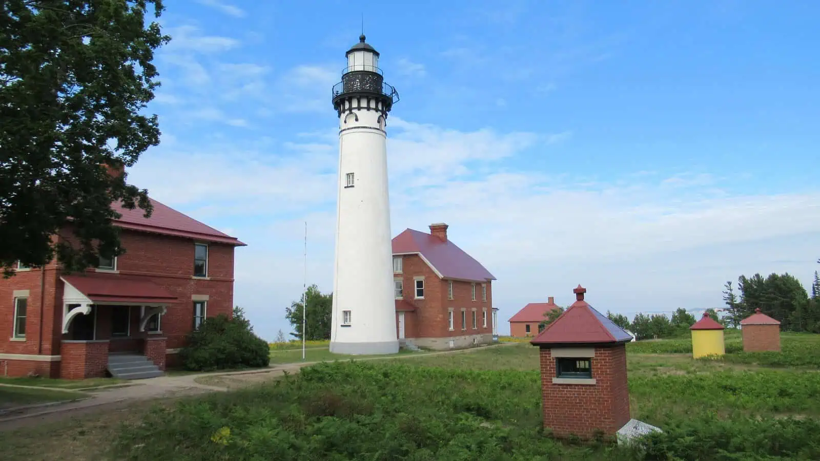 The Au Sable Light Station at Pictured Rocks National Lakeshore, the white tower rising over the brick keepers quarters and outbuildings.