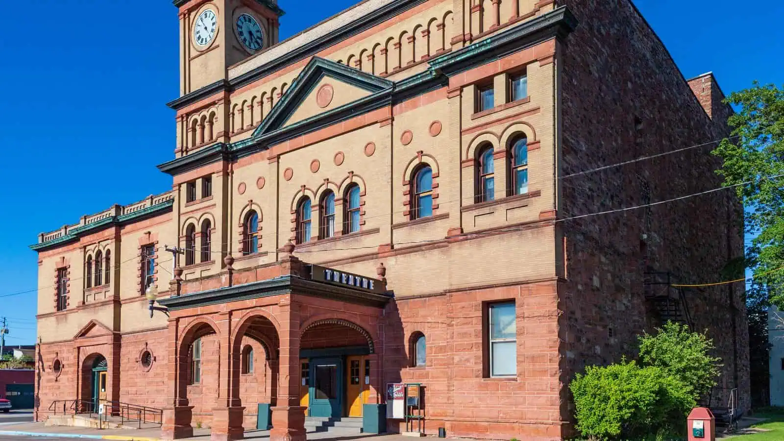 The Calumet Theatre in Calumet, Michigan, a brick and sandstone opera house with a clock tower, seen from the street corner.