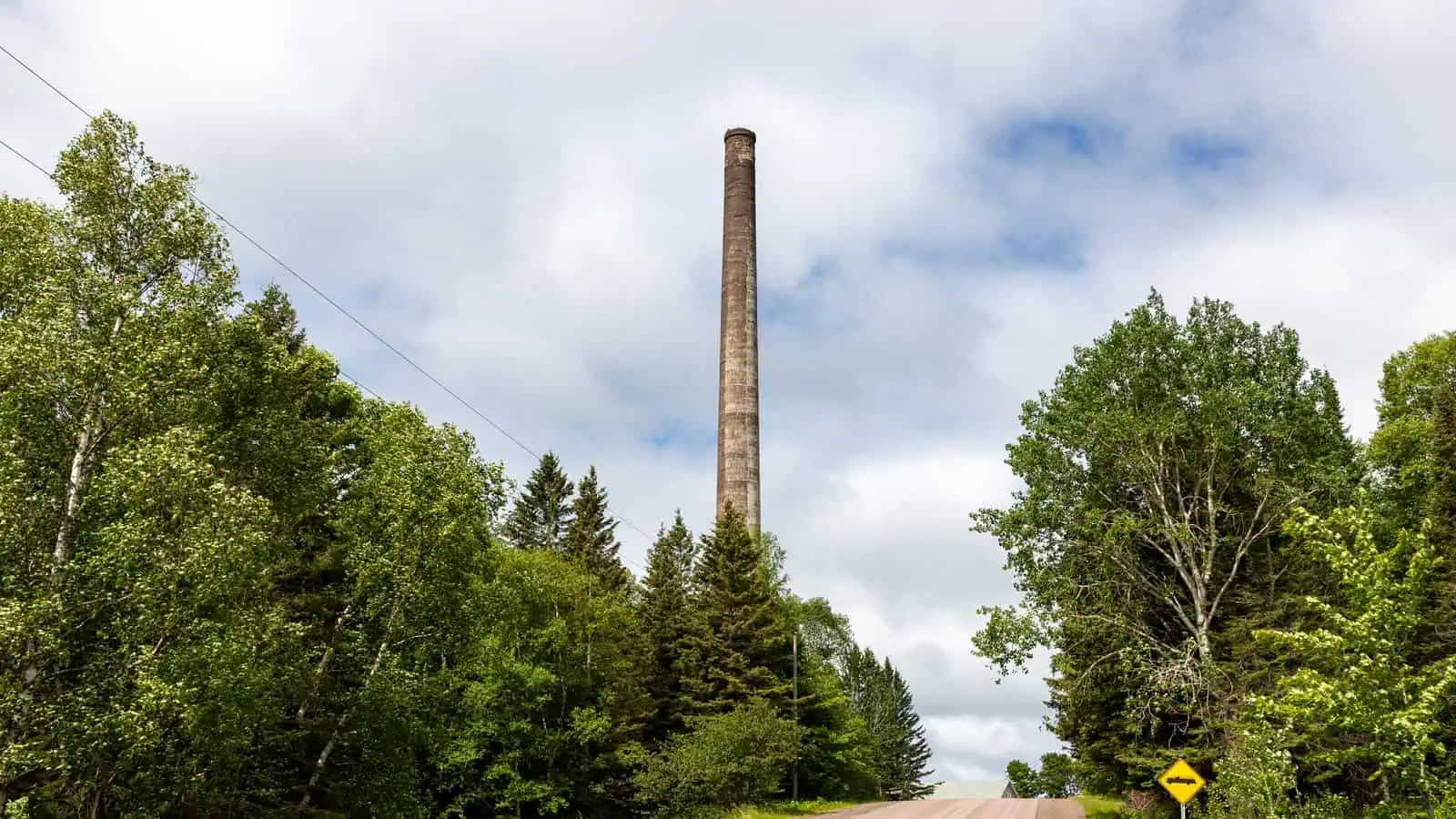 The 236-foot smokestack of the former stamp mill at Gay, Michigan, rising over the trees beside the road into town.