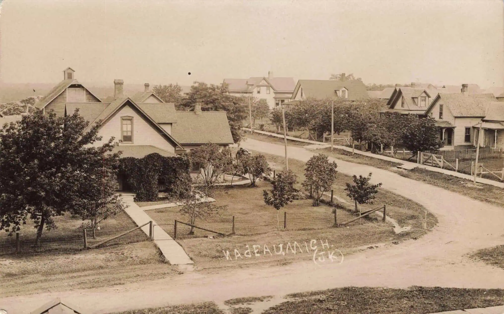 Nadeau, Michigan in 1909: a dirt street with wooden storefronts.