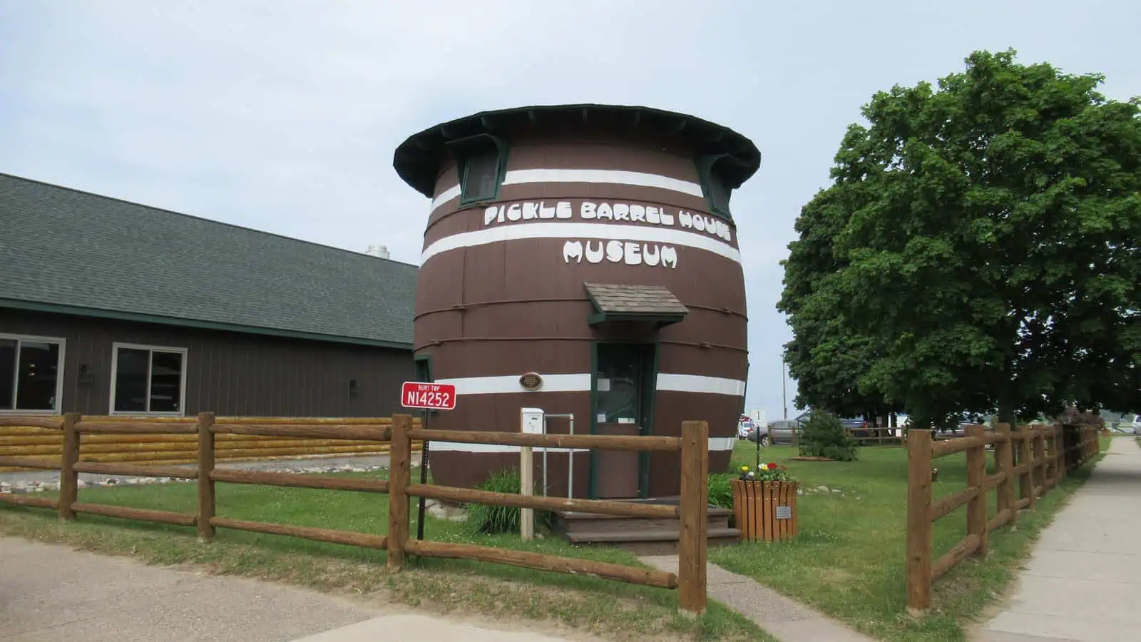 The Pickle Barrel House Museum in downtown Grand Marais, Michigan, a two-story wooden barrel building behind a rail fence.