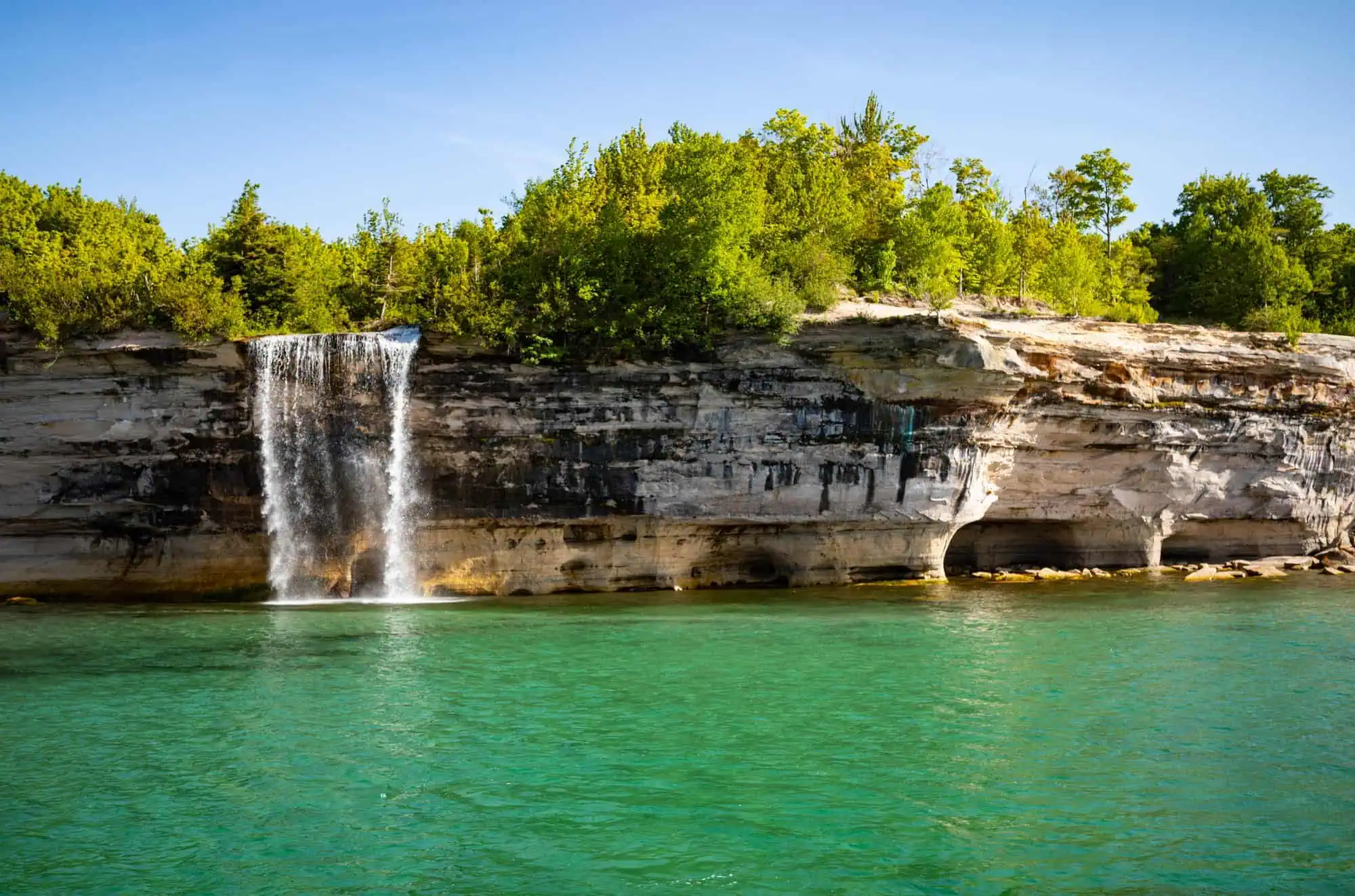 The mineral-stained sandstone cliffs of Pictured Rocks rising from Lake Superior.