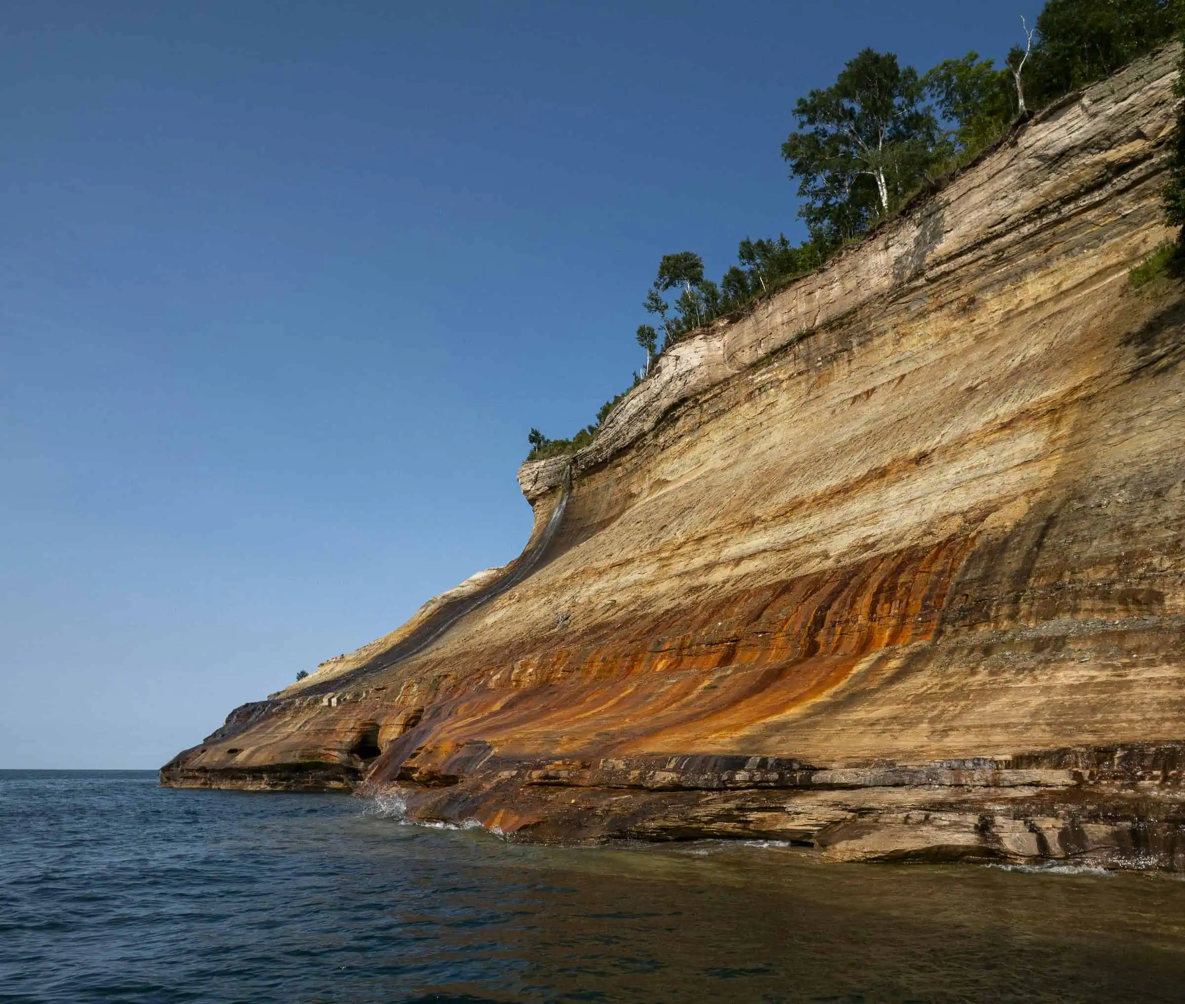 Multi-colored sandstone cliffs at Pictured Rocks National Lakeshore, streaked orange and white above Lake Superior.