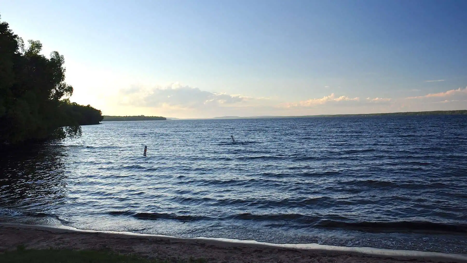 Lake Gogebic under a partly cloudy sky with a wooded shoreline at left. Photo: Skye Marthaler, CC BY-SA 3.0.